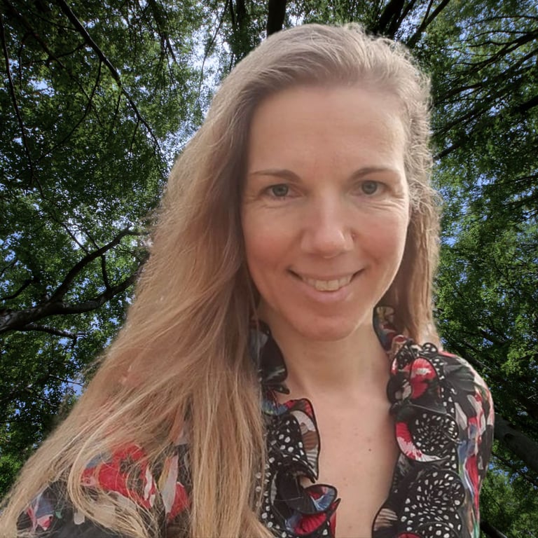Nadja Kapschefsky lächelt in die Kamera, umgeben von grünen Bäumen