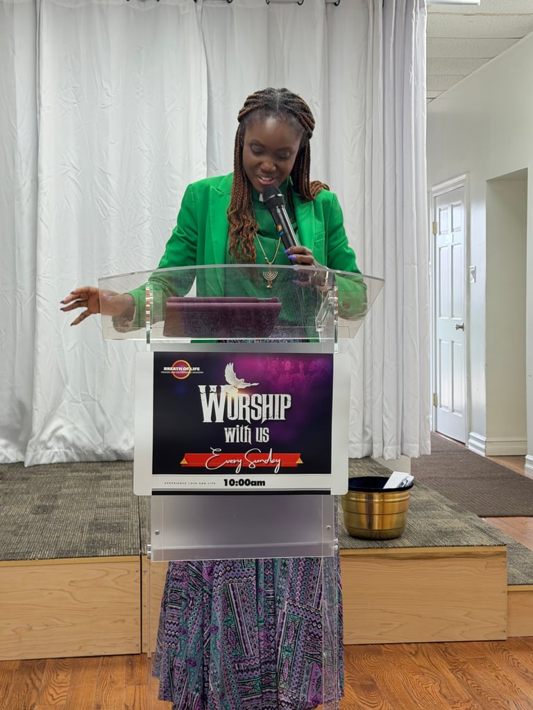 Woman in green blazer speaking at a podium with Worship with us sign during a service
