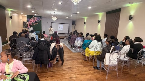 Group of people seated in modern event space with projection screen, listening to presentation or seminar