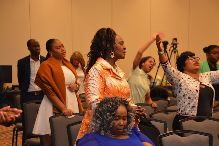 A diverse group of people standing and raising their hands in worship at Festival of Deliverance
