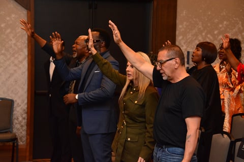 Group of people applauding and celebrating together indoors, with hands raised in joy