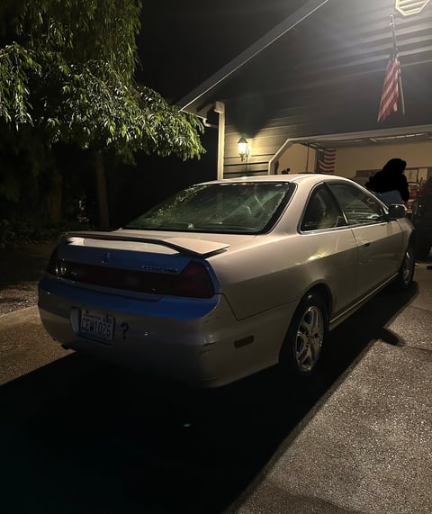 White sedan parked in driveway at night with house and garage in background