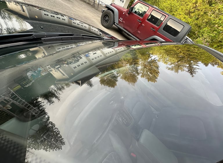 Red Hummer H2 parked on rural road with green foliage and water reflection visible