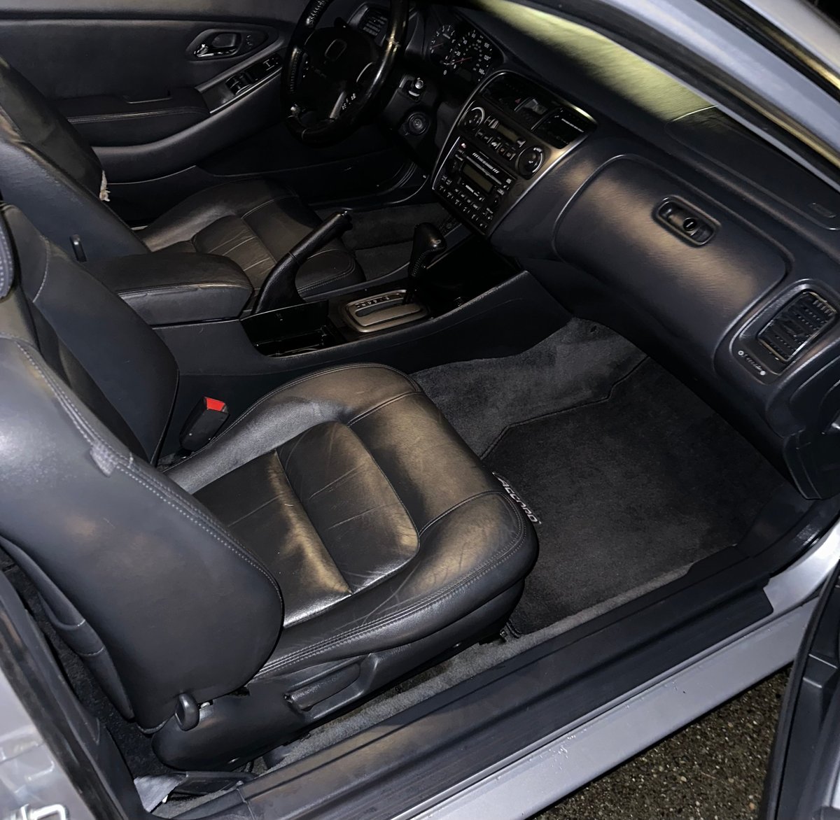 Interior view of a car showing black leather seats, steering wheel, dashboard, and center console with electronic controls