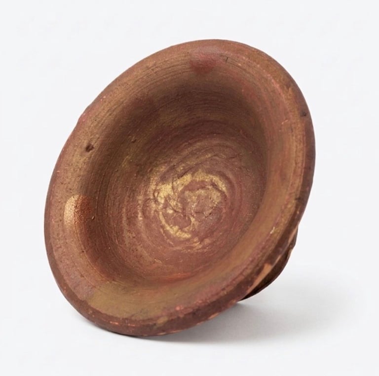 Terracotta ceramic bowl tilted at an angle, showing weathered interior with concentric rings and worn texture