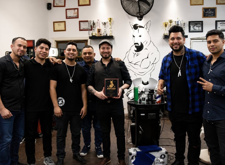 Seven men posing together in a studio with artwork and equipment visible on the walls and behind them
