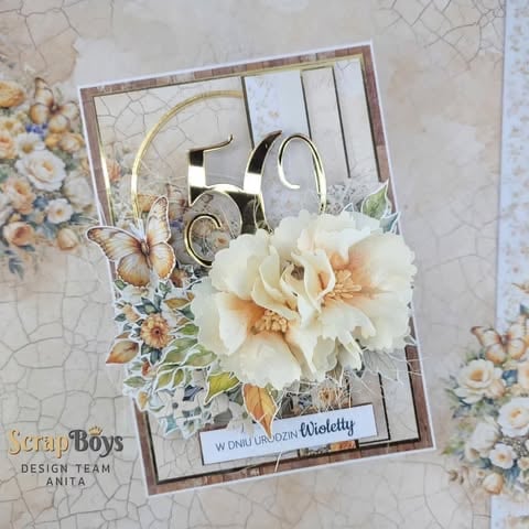 Handmade scrapbook card with cream 3D flowers, vintage frame, metallic gold 50 numerals, butterfly, and decorative floral patterns on textured background
