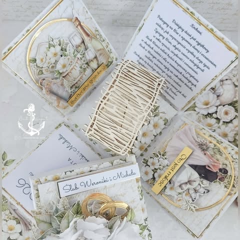 Flat lay of wedding stationery and décor with white flowers, embroidery hoops, gold accents, and handwritten invitations on white background