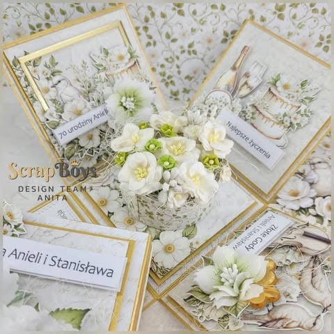 Flat lay scrapbook design with white and cream 3D flowers, gold-framed cards, dried botanicals, and personalized text tags 'Anieli i Stanisława', '70 urodziny', 'Najlepsze życzenia' by ScrapBoys Anita