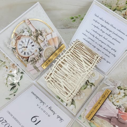 Flat lay of wedding stationery and decor including invitation cards, a vintage clock, dried flowers, twine, and gold accents arranged on a white surface