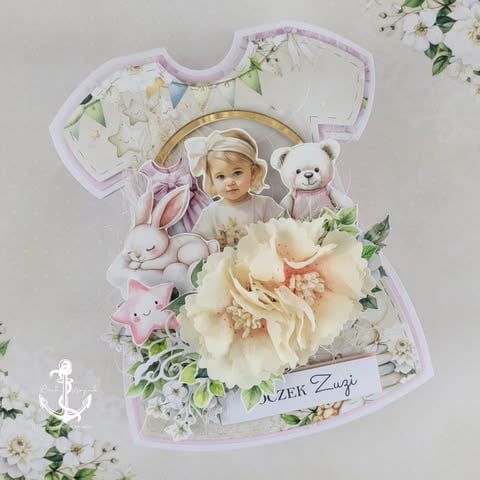 Decorative baby dress-shaped scrapbook with photo of child, teddy bear, bunny, flowers, and text, pastel color scheme