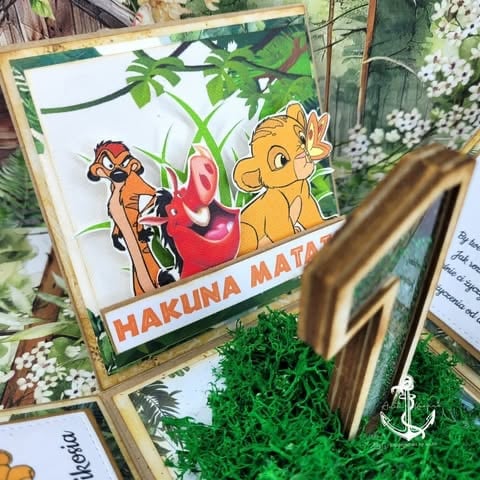 Hakluna Matata sign with cartoon lion cub and meerkat characters among decorative plants and gold accents