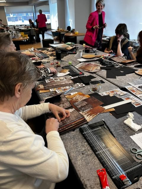 Group of people working on collage art projects at a long table in a bright workshop studio