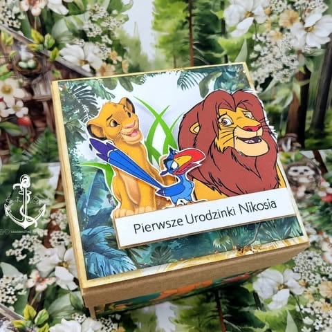 Wooden box with Lion King characters Simba and Mufasa illustration and Polish text Pierwsze Urodzinki Nikosia on floral background