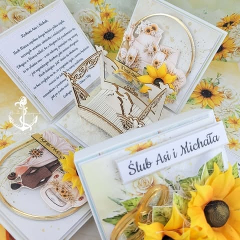 Flat lay of wedding stationery with sunflower decorations, including invitation cards, a CD, and anchor and flower embellishments in yellow and white.