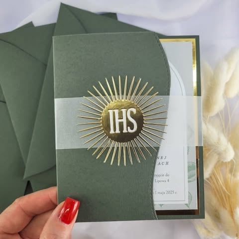 Hand holding green religious card with gold sunburst IHS symbol and white ribbon band, sage green envelope