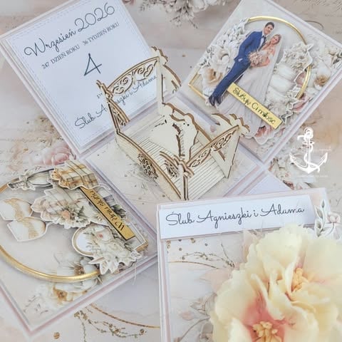 Flat lay of wedding memorabilia including invitation, photo of bride and groom, gold accessories, and blush pink rose on white surface
