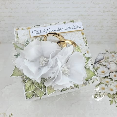 Wedding greeting card with white flowers, gold rings, and personalized name tag on decorative floral background
