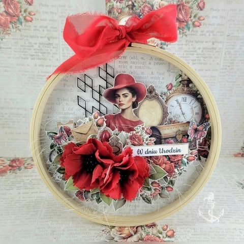Vintage-style embroidery hoop ornament with woman in red hat, red flowers, clock, and 'W dniu Urodzin' text, tied with red ribbon bow
