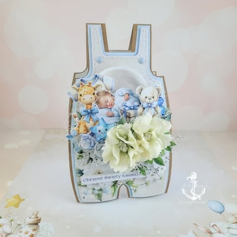 Decorative baby shower card shaped like a romper featuring toys, flowers, and blue accents on white background.
