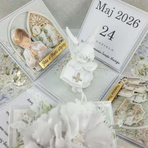 White communion keepsake display with religious cross ornament, photo, calendar showing May 26, and white flowers.