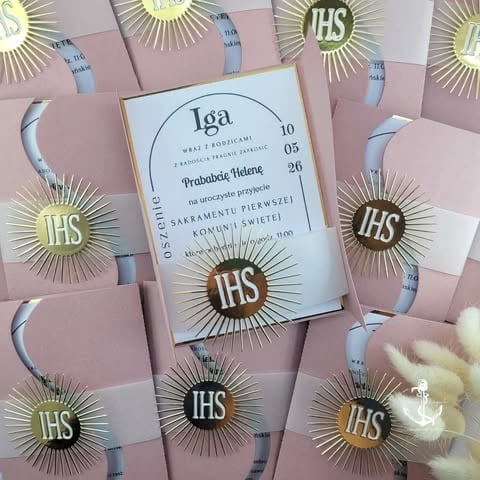 Religious pamphlets with gold IHS monogram and sunburst symbols arranged on pink background with white religious invitation card 'Iga' in center
