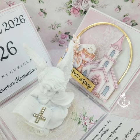 Flat lay of religious mementos including a white cross charm, ornamental church decoration in a gold hoop, calendar, and rose-themed stationery.