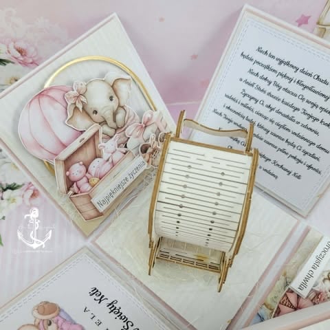 Flatlay of decorative stationery items including a teddy bear in a basket, miniature chair, and note cards on a pink floral background