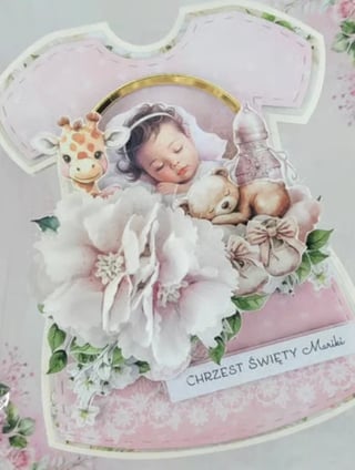 Religious greeting card with sleeping baby angel surrounded by white flowers, giraffe toy, and gold halo with Polish text