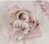 Newborn baby sleeping peacefully on pink bedding surrounded by soft blankets