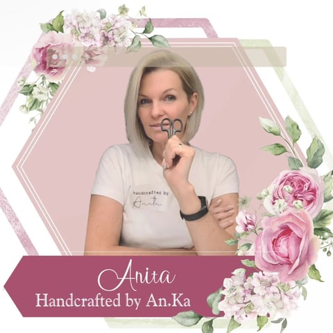 Portrait of Anita wearing a cream graphic tee, positioned in a decorative hexagonal frame with pink peonies and greenery on a pink background, labeled Handcrafted by An.Ka