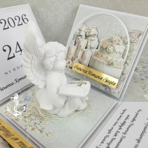 Flat lay of opened books displaying white decorative items, dried flowers, and a small white figurine sculpture.
