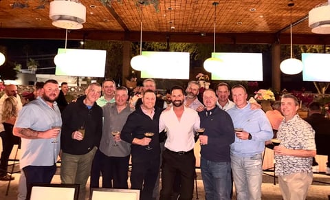 Group of men posing together in a modern venue with wooden ceiling and pendant lights