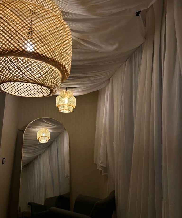 Elegant hallway with draped white ceiling fabric, woven rattan pendant lights, and warm golden lighting