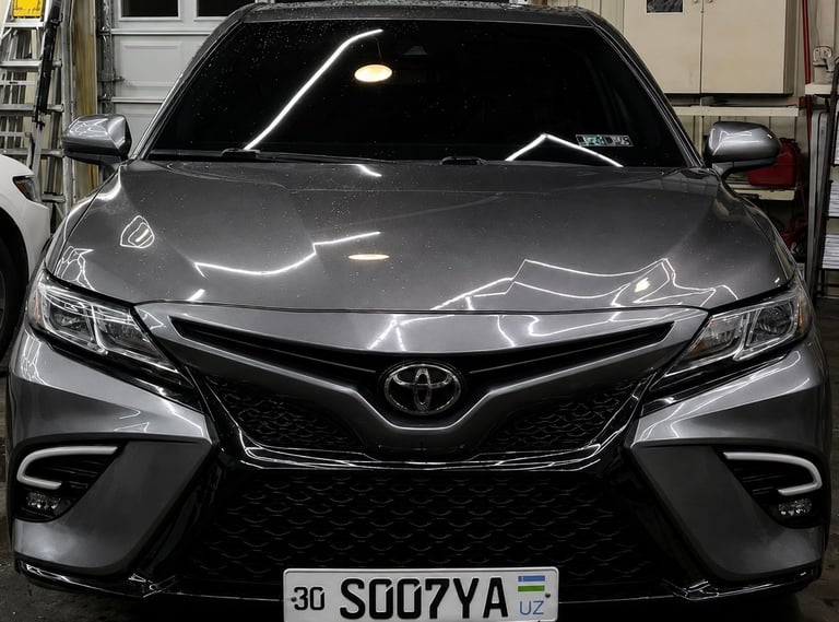 Front view of a silver Toyota Camry parked in a garage with LED headlights and UK license plate visible