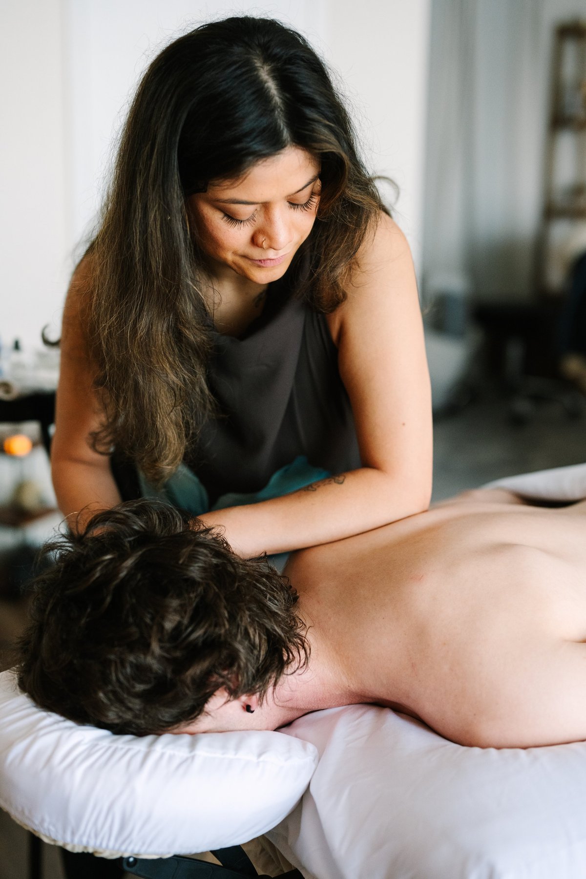 Massage therapist performing therapeutic massage on a client's back in a clinical setting