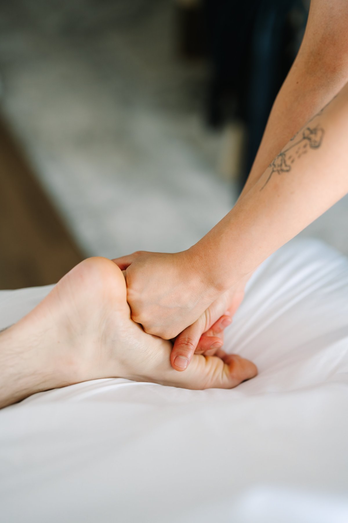 Two people holding hands in a tender gesture, one person wearing white fabric with a small arm tattoo visible