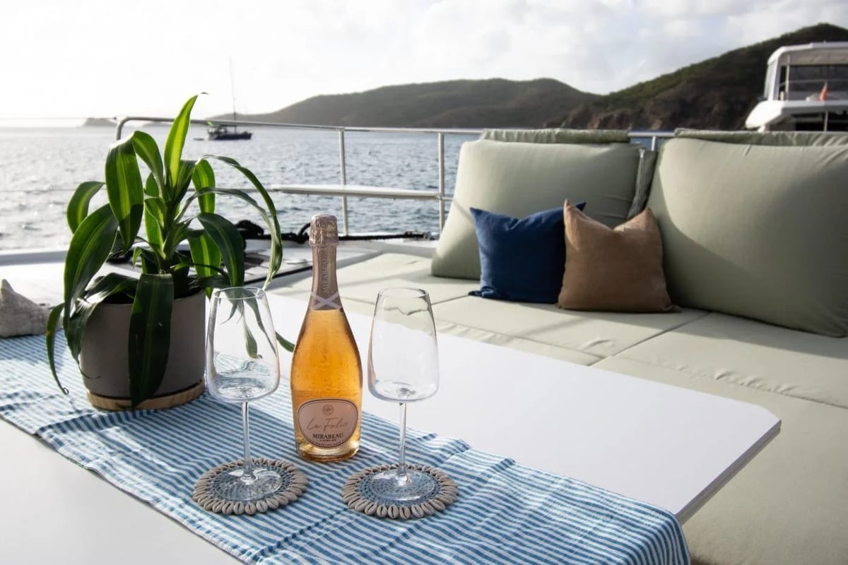 Allegra — luxury yacht deck with wine, glasses, and coastal mountain views