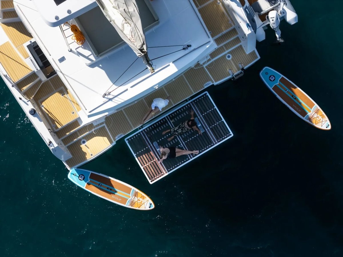 Allegra — aerial view of a white catamaran with solar panels moored in clear turquoise water