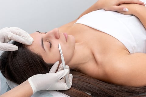 Woman receiving facial treatment with professional applying product to her face with applicator pen