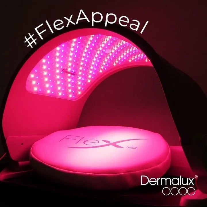 Dermalux red light therapy device with LED panel glowing pink against dark background