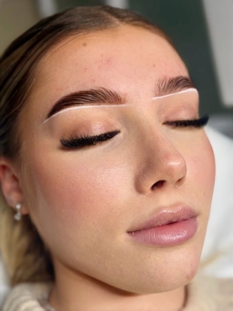 Close-up profile of a womans face showing professional eye makeup with defined brows, black eyeliner, and natural skin tone