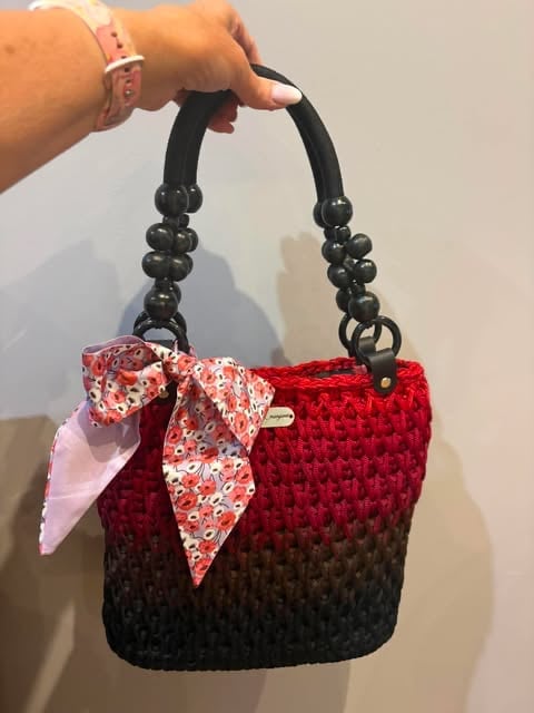 Czerwono-czarna pikowana torebka z czarnymi koralikowymi uchwytami i kwiatową kokardą.
