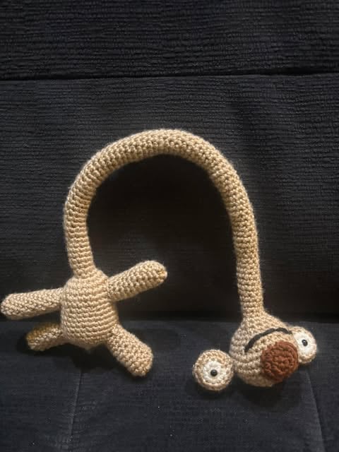 Zabawna szydełkowa maskotka w kształcie robaka z długą szyją i rączkami — handmade amigurumi.
